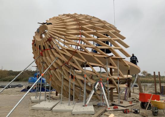 a man standing next to a wooden structure