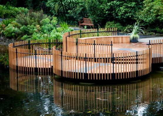a wooden deck with a fence in the middle of a pond