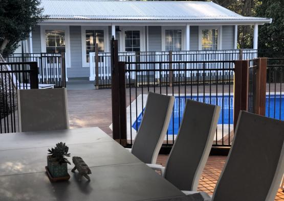 a table and chairs on a deck with a pool in the background