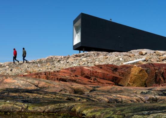 a man walking on a rocky hill with a building in the background