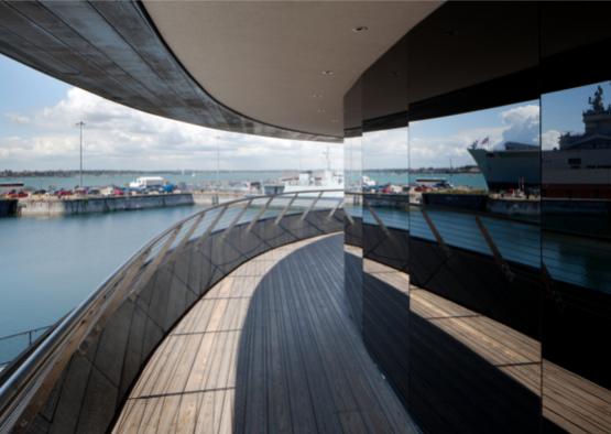 a circular building with a view of a harbor and ships