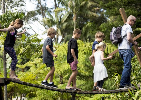 a group of kids walking on a wooden bridge