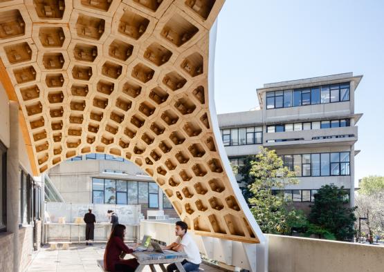 people sitting on a bench under a structure