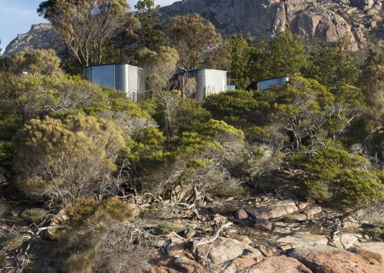 a group of metal containers on a hill with trees and rocks
