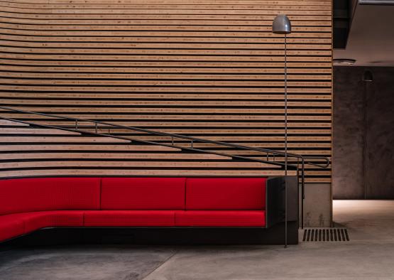 a red couch in front of a wood wall