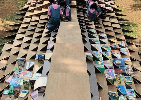 a group of people sitting on a bench with books on it