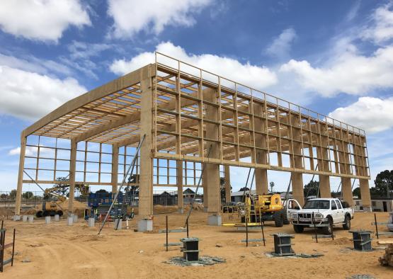 a building under construction with trucks and a blue sky