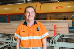 Danny Watson standing in front of Hundegger machine wearing high-vis