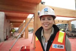 Women wearing high-vis and hard hat standing in front of a mass timber construction site.