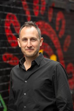 Man standing against background of Aboriginal artwork