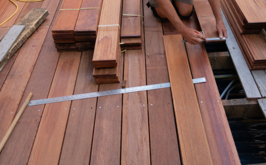 person bent down installing timber boards into decking system
