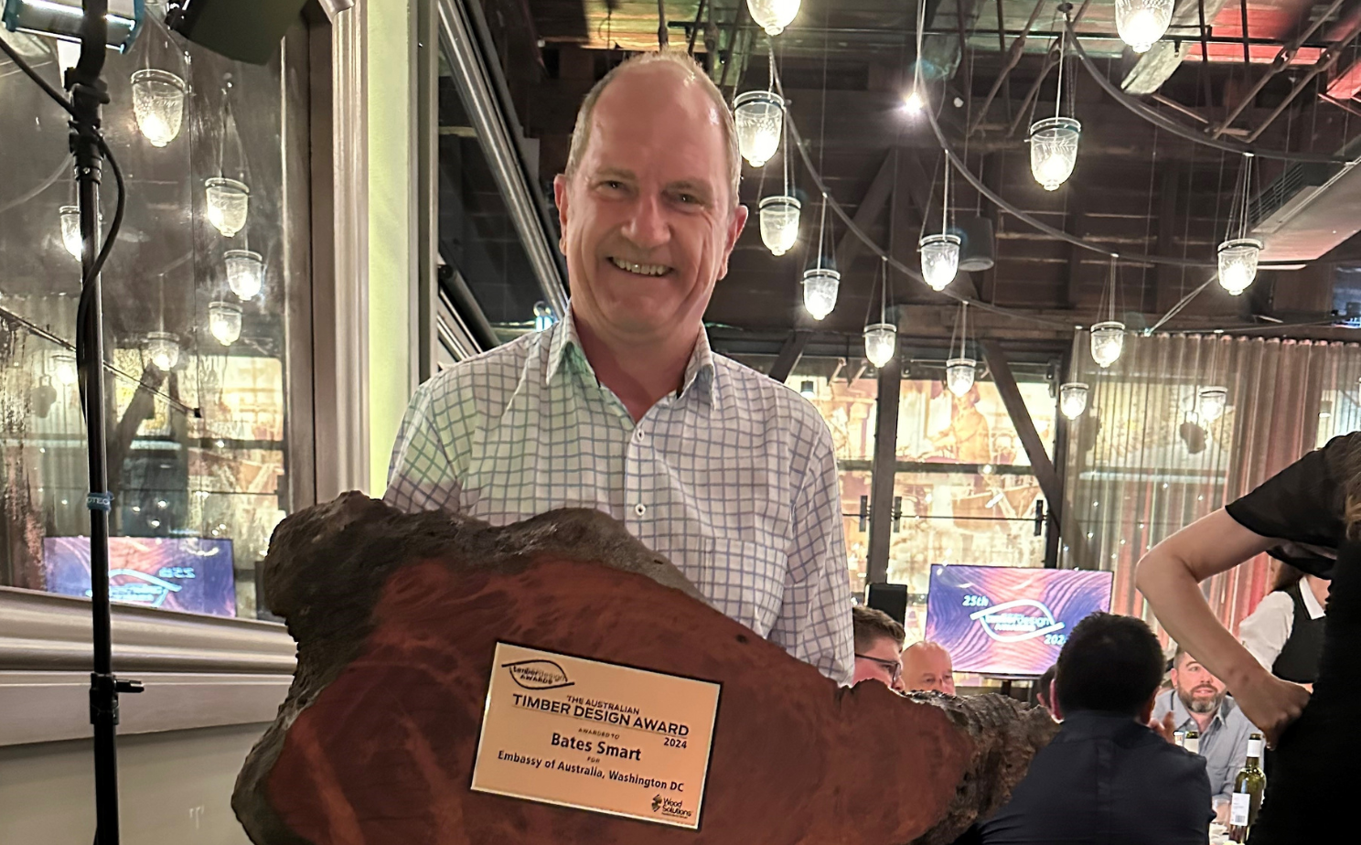 Image of man holding wood cross section award trophy