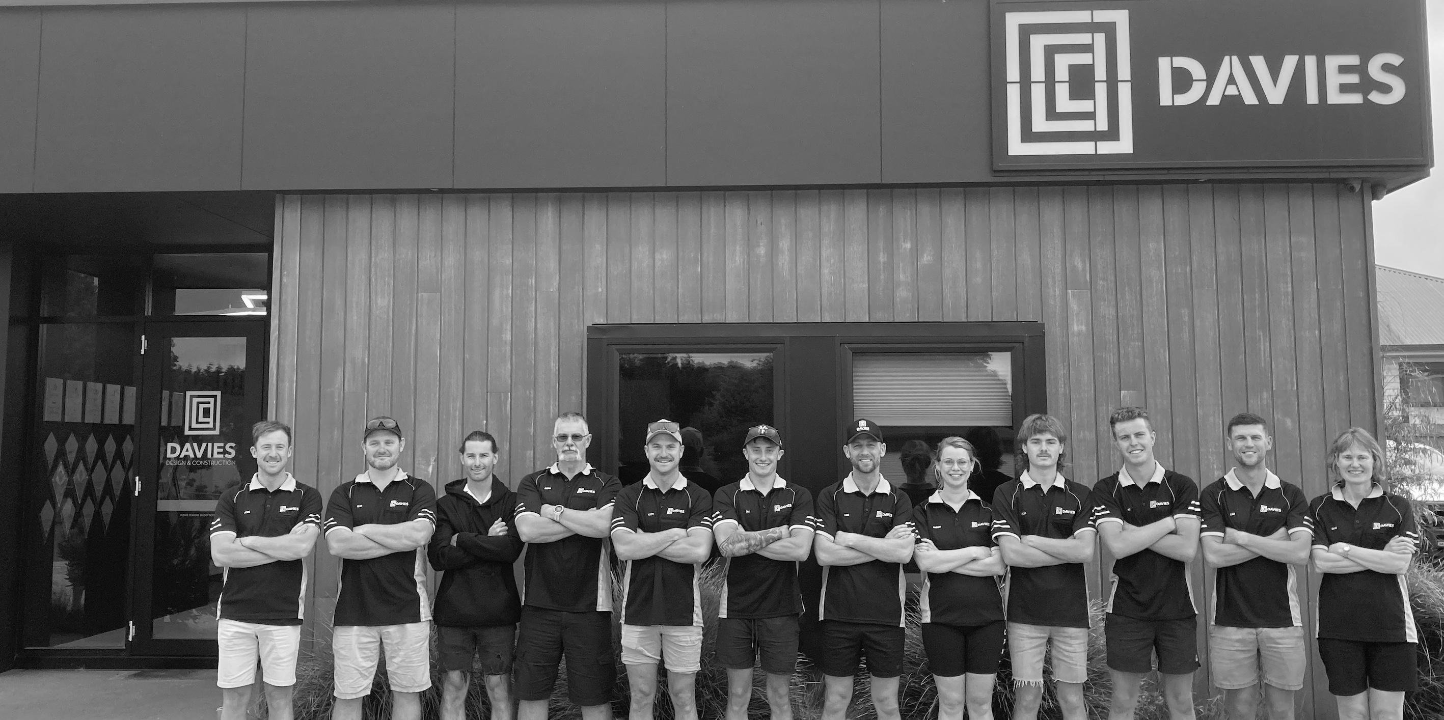 Black and white image of building team under Davies Construction sign