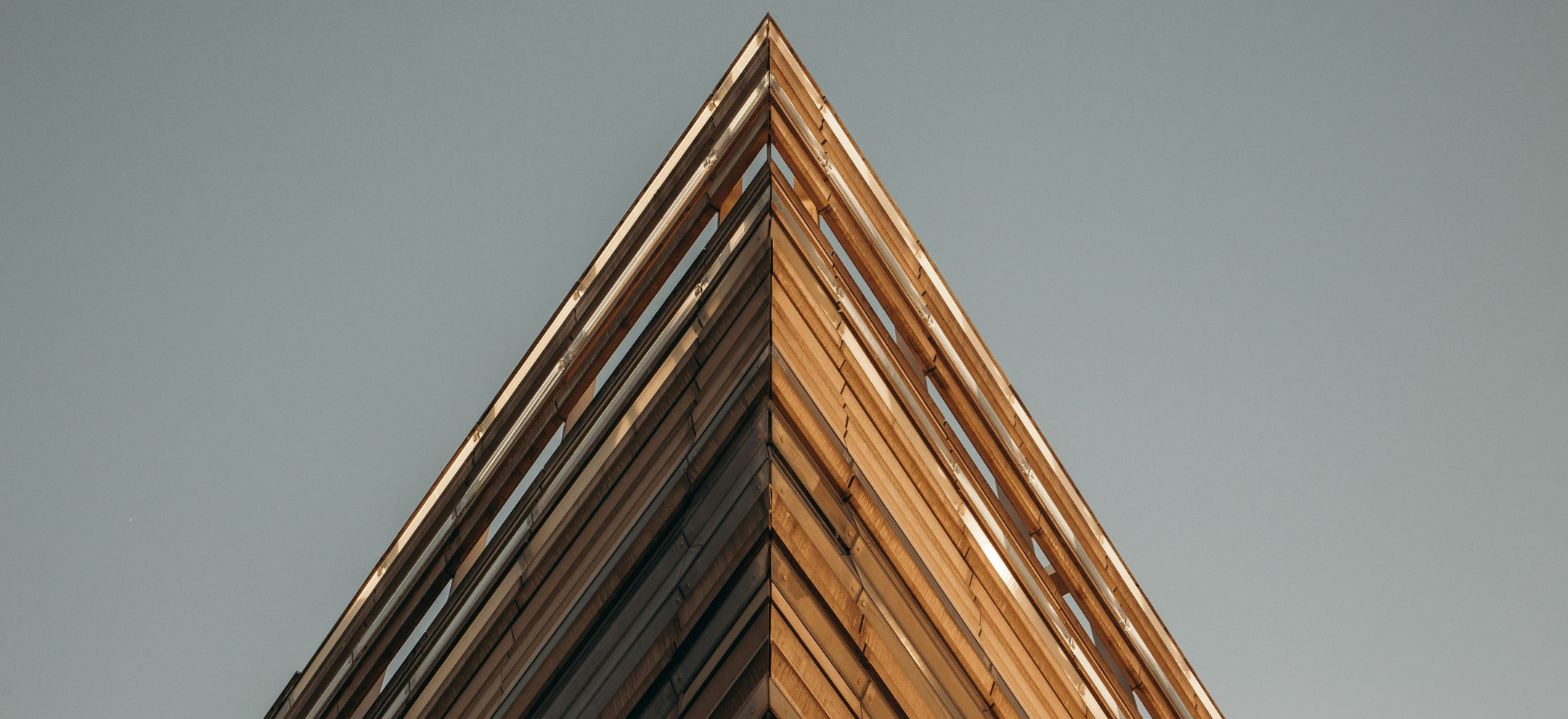 Edge of building made from recycled timber against grey sky