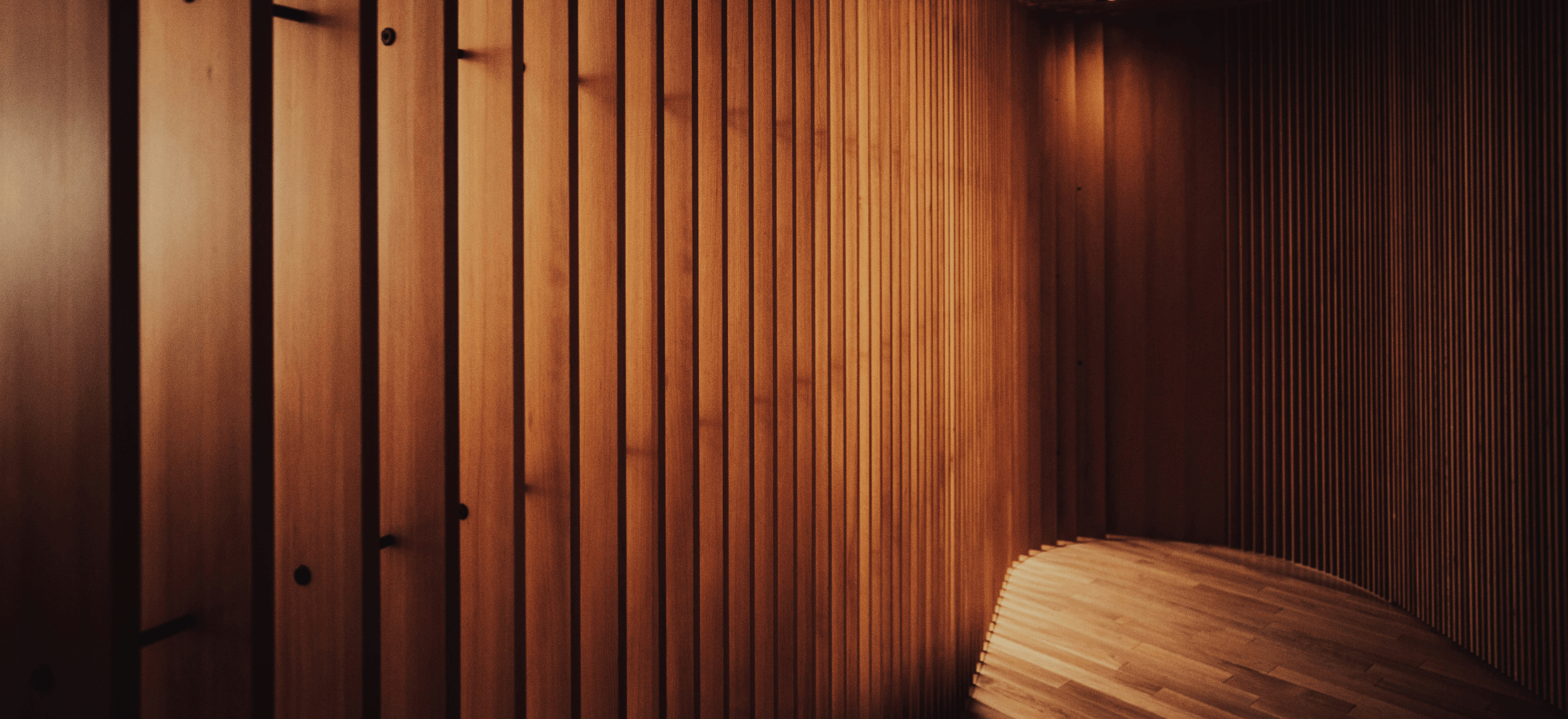 Looking down a timber clad hallway with timber floors and moody lighting