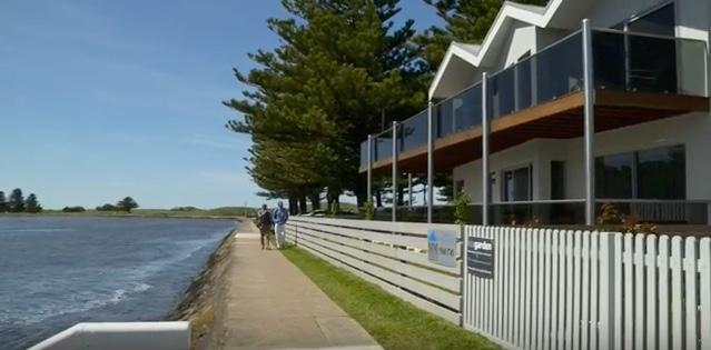 a couple walking on a sidewalk next to a white fence