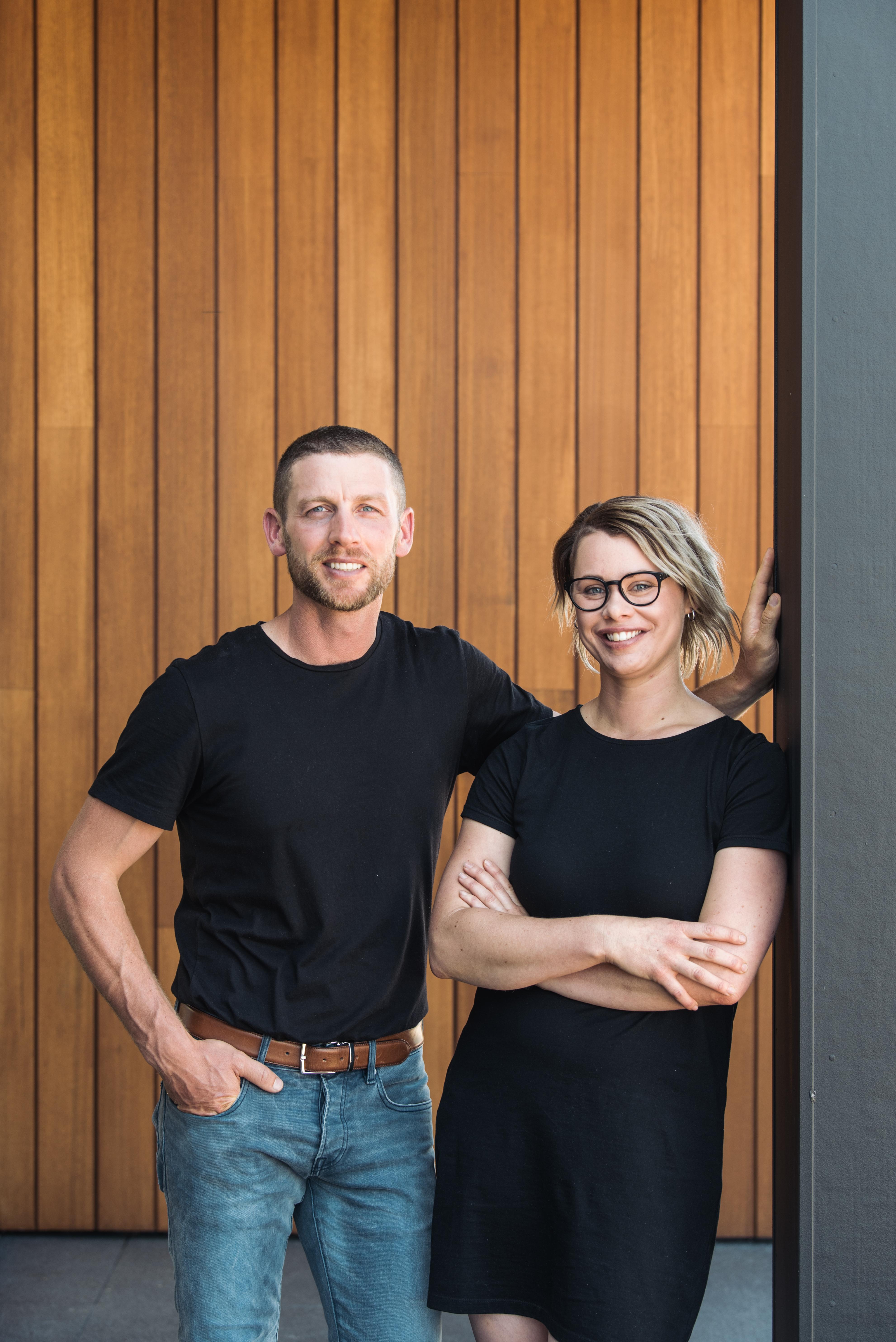 A man and woman standing in front of a timber wall