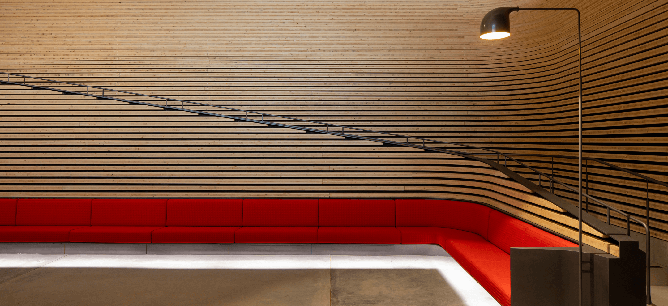 Timber walls surrounding a bright red wrap around couch