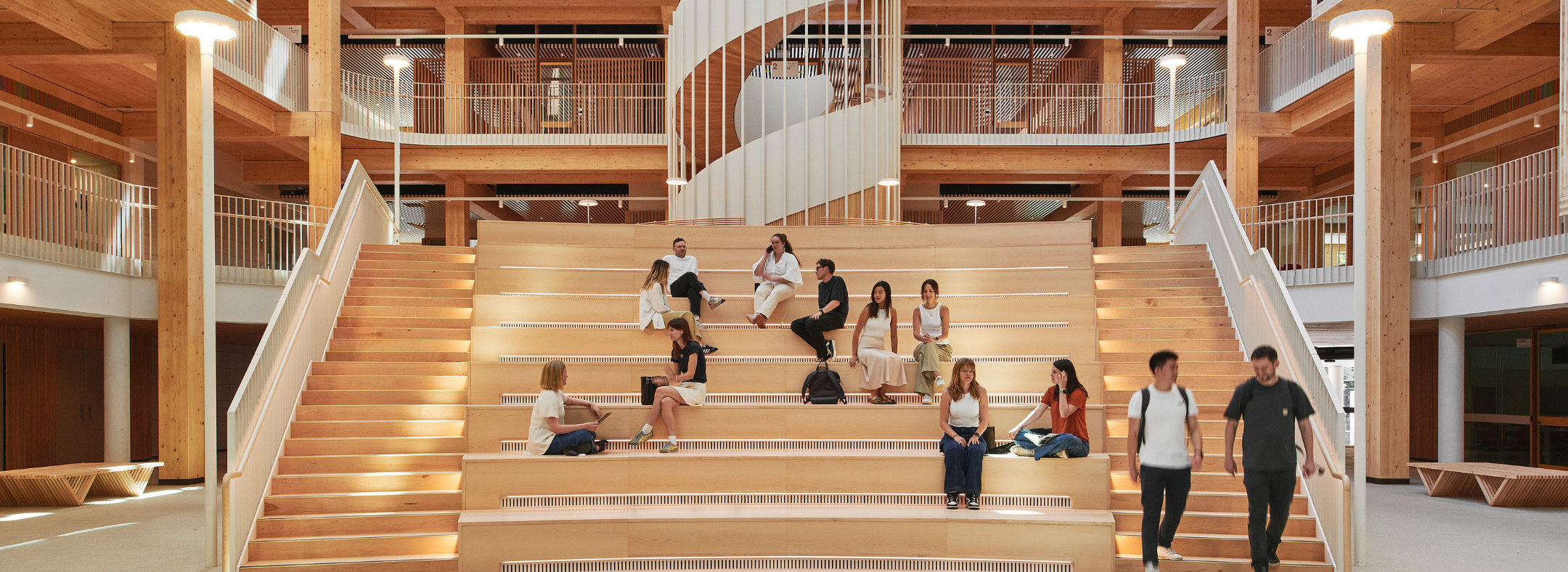 Students sitting on sprawling timber staircase and walking down the side stairs