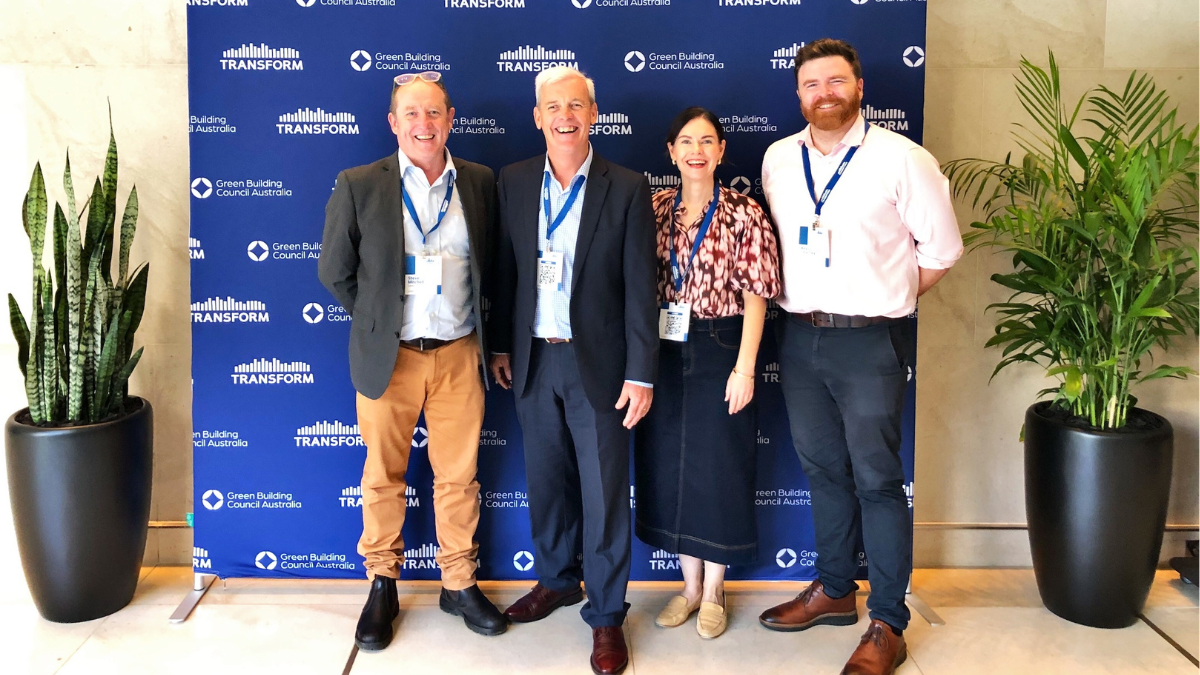 Four people posing in front of blue media wall