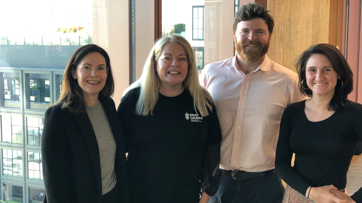 Four people posing by glulam beam