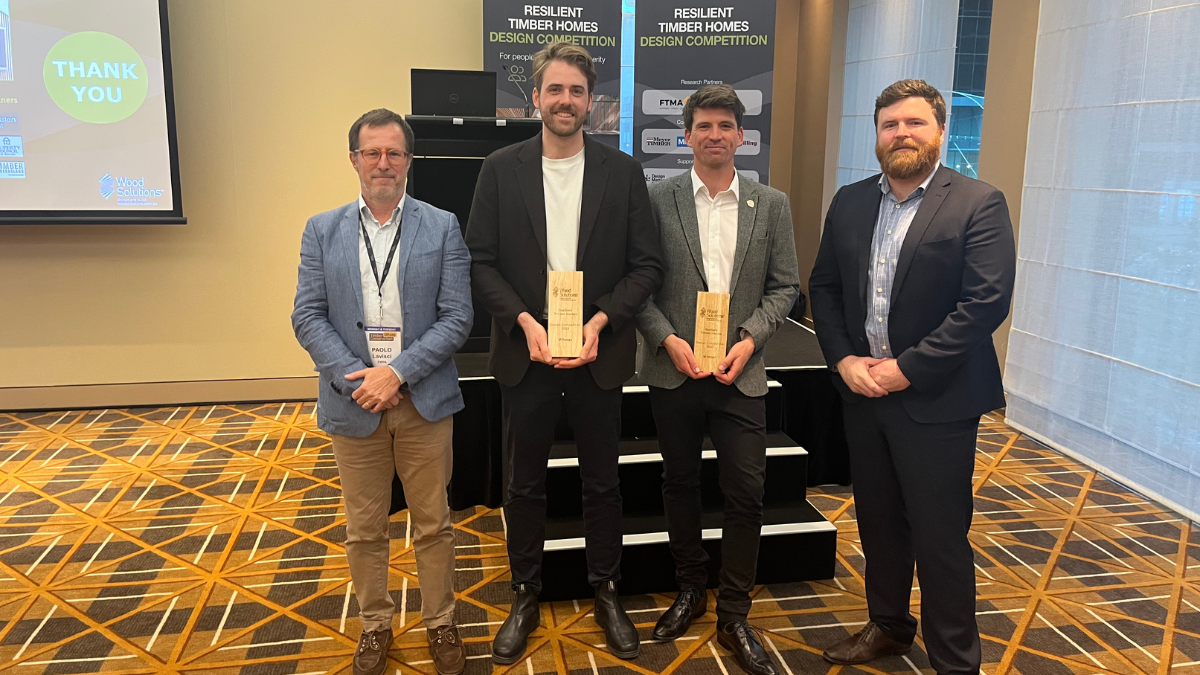 Four men posing - two are holding awards