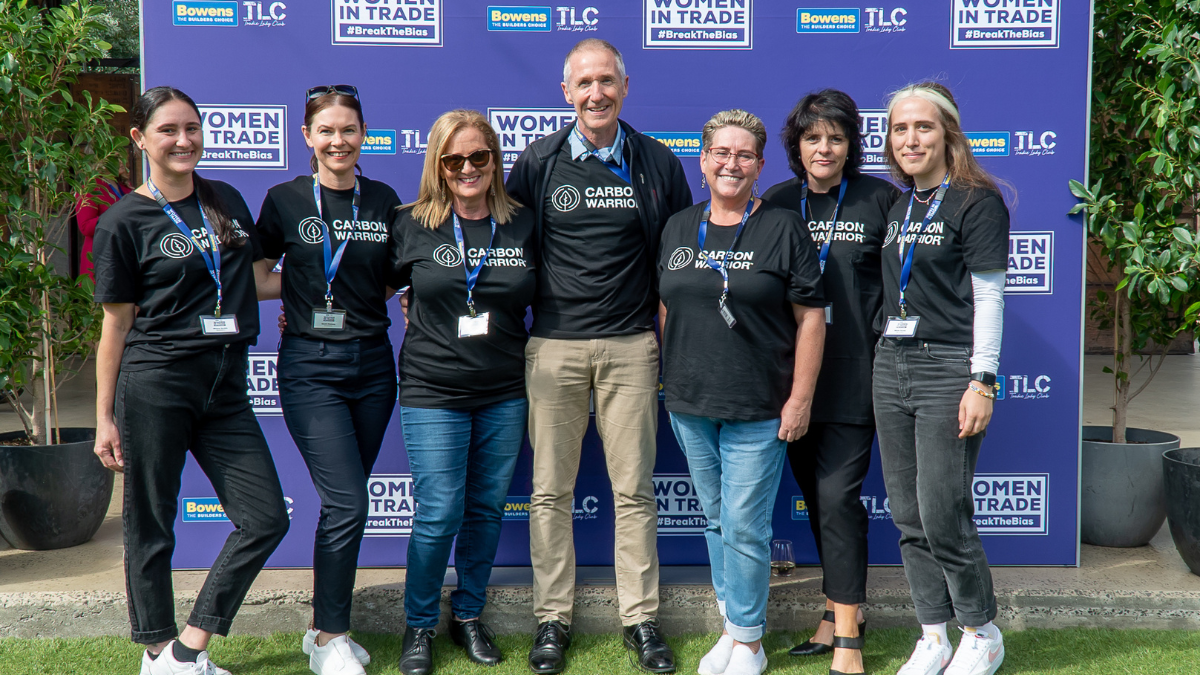 Seven people posing in front of purple media wall