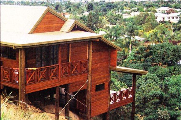 a person standing on a wooden house with Jim Thompson House in the background