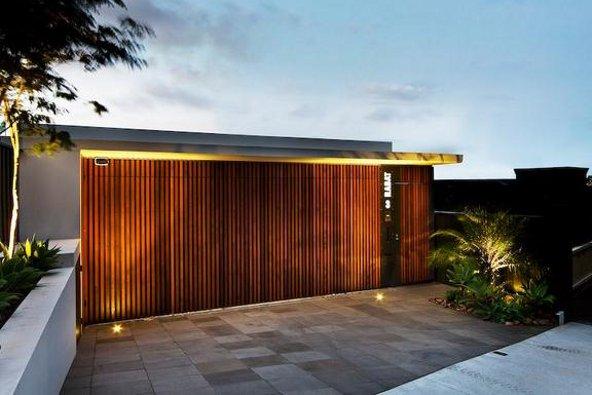 a building with a wood wall and a tile driveway