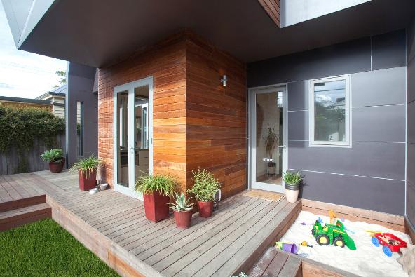a wooden deck with a sandbox and potted plants