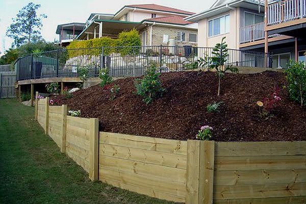 a wooden fenced hillside with plants and a fenced yard