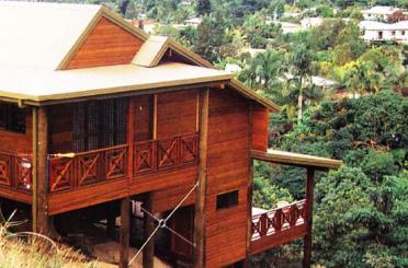 a person standing on a wooden house with Jim Thompson House in the background