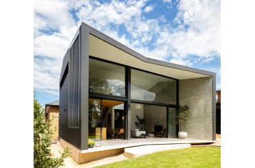 a house with a concrete wall and glass walls