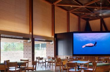 a room with tables and chairs and a large screen