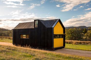 a black and yellow house on a dirt road