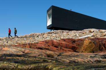 a man walking on a rocky hill with a building in the background